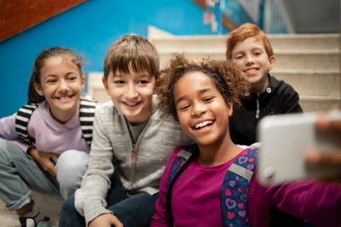 Mutlu gülümseyen okul çocukları okulda grup fotoğrafı çekiyor..