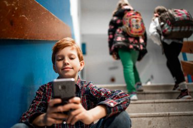 Okuldaki akıllı telefonunu kullanan ve interneti karıştıran ya da sosyal ağları kontrol eden genç bir öğrenci..