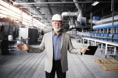 Kıdemli fabrika CEO 'su ya da iş elbisesi içindeki yönetici endüstriyel üretim departmanında yürüyor ve üretim sürecini kontrol ediyor..