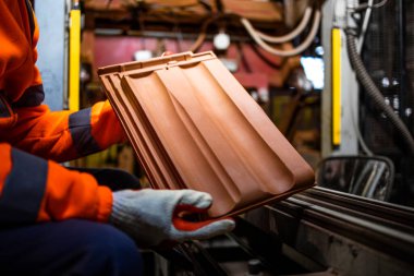 Çatı kiremitleri ya da inşaat endüstrisi için kiremit üretimi. Fabrika işçisi üretim salonundaki fayansları tutuyor..