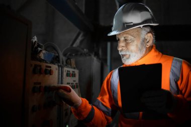 Sanayi mühendisi elektrikçi üretim fabrikasındaki elektrik kabinlerinin arızasını ve elektrik tesisatını kontrol ediyor..