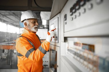 Üretim veya imalat için endüstriyel makineler üzerinde parametreler belirleyen profesyonel fabrika mühendisi.