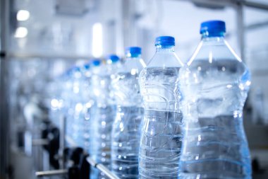Şişeleme fabrikasındaki plastik su şişelerinin görüntüsü taşıma bandı otomatik makinesiyle taşınıyor..