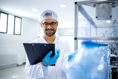 Deneyimli fabrika işçisi şişeleme fabrikasında içme suyu üretimini kontrol ediyor..