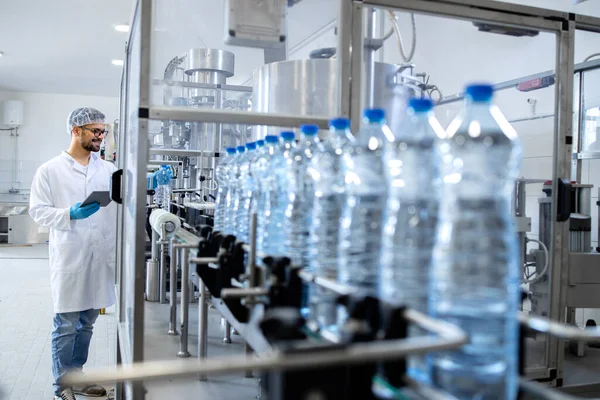 Karbonatlı şişe suyu üretimi. Şişeleme fabrikasında kalite kontrolü yapan deneyimli bir teknoloji uzmanı..