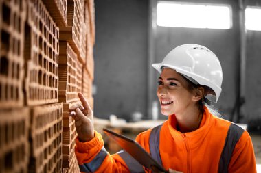 Kadın fabrika işçisi tuğla fabrikasındaki sevkiyattan önce ürünlerin kalitesini kontrol ediyor..