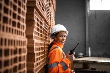 İnşaat alanındaki tuğla yığınının yanında duran kadın inşaat işçisinin portresi..