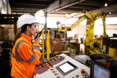 Fabrikadaki endüstriyel üretim sürecini kontrol eden güvenlik ekipmanlarında çalışan kadın işçiler.