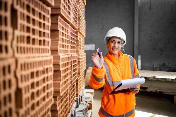 Endüstriyel kadın işçi inşaat alanına gönderilmeye hazır tuğla envanterini kontrol ediyor..