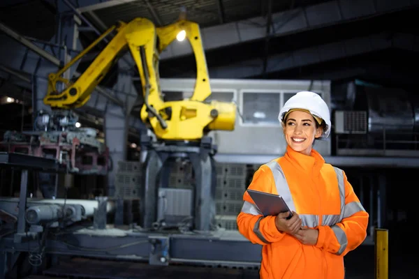 Fabrikadaki endüstriyel üretim süreci ve tablet bilgisayarındaki üretimi kontrol eden kadın işçi..