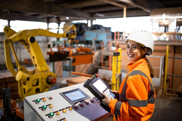 Sanayi robotu kullanan ve üretim tesisinde üretim sürecini izleyen kadın fabrika işçisinin portresi.