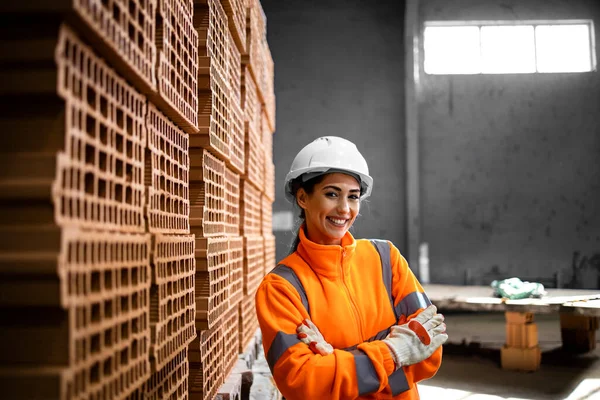 安全装置を装着した女性労働者の肖像と工場倉庫内の製品の横に立つ女性労働者 — ストック写真