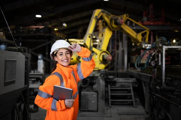 Endüstriyel robot kol makinesinin önünde duran kadın fabrika mühendisinin portresi.