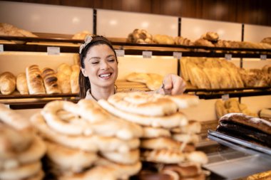 Güzel gülümseyen fırın işçisi fırındaki müşteriye taze pasta satıyor..