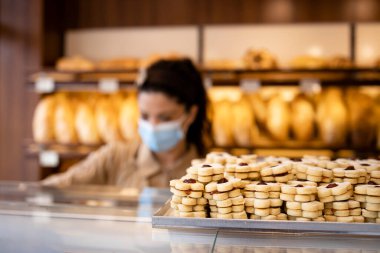 Pastanedeki lezzetli ve lezzetli kurabiyelere ve arka planda yüz maskesi olan işçilere yakından bakın..