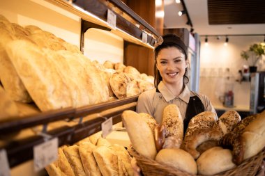 Üniformalı güzel kadın şarküteri işçisinin portresi elinde sepet dolusu taze hamur işi ve süpermarkette yetişmiş..