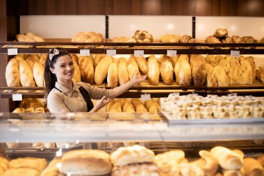 Fırında fırın işçisinin portresi fırında taze hamur işleri ve ekmek gösteriyor..