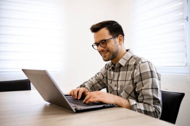 Dizüstü bilgisayarında yazan yazılım mühendisi ya da programcı şirket ofisinde yeni bir uygulama geliştiriyor.