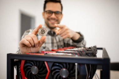 Bitcoin tutan uzman programcının portresi ve kripto para madencilik platformunun yanında duruyor..