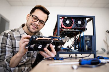 Bitcoin madenci uzmanı yeni kripto para birimi donanımı kuruyor ve madencilik için grafik kartını kontrol ediyor.