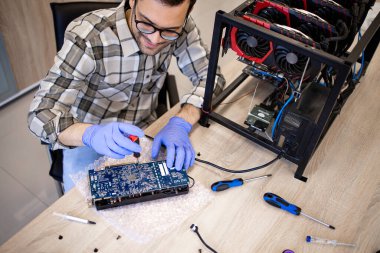 Servisçi bitcoin madencilik platformu için grafik kartı onarıyor.