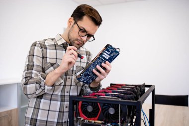 Bitcoin madenci uzmanı yeni kripto para birimi donanımı kuruyor ve madencilik için grafik kartını kontrol ediyor.