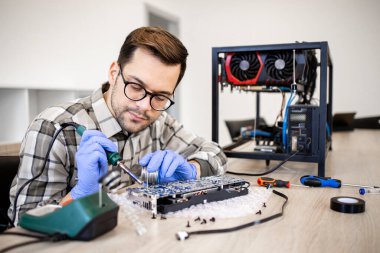 Profesyonel servis elemanı grafik kartını onarıyor ve yazdırılmış devre kartını lehimliyor.