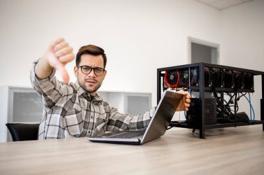 Programcı bitcoin değerini ve kripto para biriminin kazancını kontrol ediyor ve başparmaklarını aşağıda tutuyor.