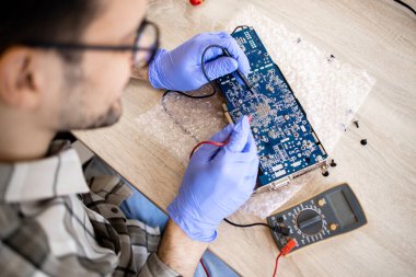 Elektronik cihazı tamir eden ve bilgisayar servisindeki ana kart voltajını kontrol eden bir uzman..