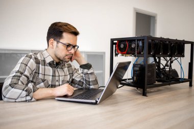 Programcı şifreleme para madenciliği için bir maden platformu kuruyor ve dizüstü bilgisayar uygulamasındaki bitcoin kazanç verilerini kontrol ediyor.