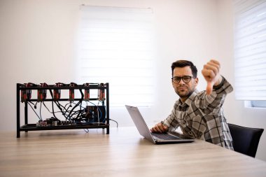 Programcı kripto para madencilik donanımı üzerinde çalışıyor bitcoin değerini kontrol ediyor ve parmaklarını aşağıda tutuyor. Bitcoin değeri azalıyor.