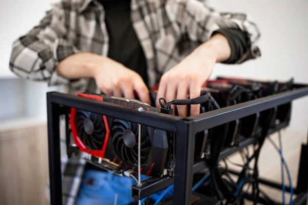 Unrecognizable person or an expert building new mining rig for bitcoin cryptocurrency. Blockchain technology and graphic cards in row.