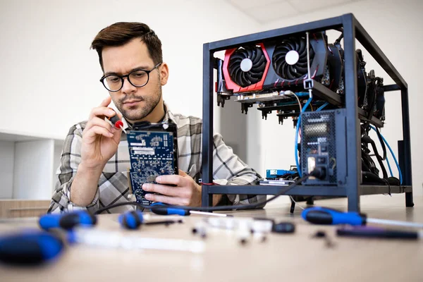Bitcoin madenci uzmanı yeni kripto para birimi donanımı kuruyor ve madencilik için grafik kartını kontrol ediyor.