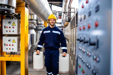 Kimyasallar için plastik kaplar taşıyan rafineri işçisi..