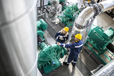 Rafineri işçileri veya mühendisler gaz borularını ve jeneratörlerin işlevselliğini inceliyor. Petrokimya endüstrisi ve petrol üretimi.