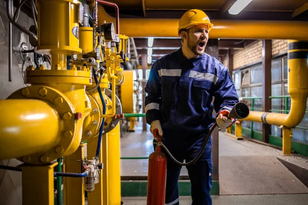 Yangın, patlama ve gaz rafinerisinde acil durum. Sanayi işçisi elinde yangın söndürücü tutuyor..