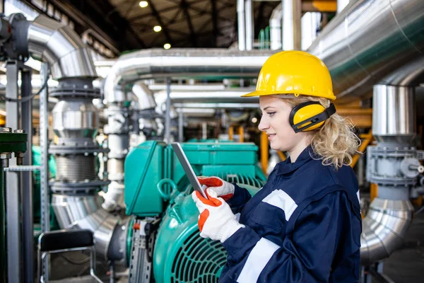 An experienced factory engineer checking production parameters of oil and gas production in refinery plant.