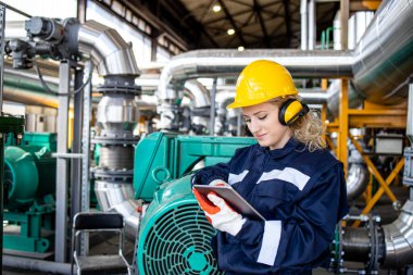 Petrol ve gaz rafinerisinde tablet bilgisayarda çalışan kadın fabrika işçisi..