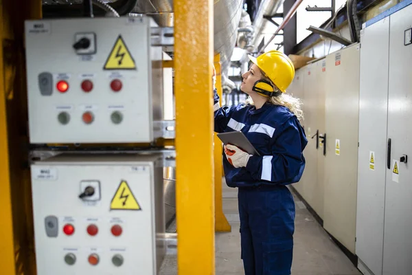 Professional industrial electrician checking voltage parameters in power plant.