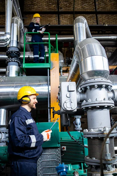 Professional power plant worker checking generator engines and pipeline installations.