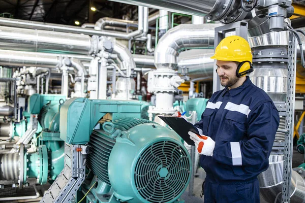 Power plant worker checking pressure and parameters in production room.