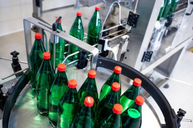 Şişelenmiş su, içecek fabrikasında taşıma bandıyla otomatik makineyle taşınıyor..