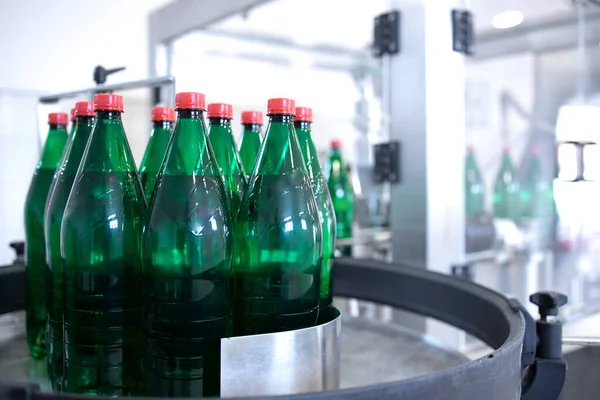 Industrial production of drinking water and bottles being moved on conveyor belt.