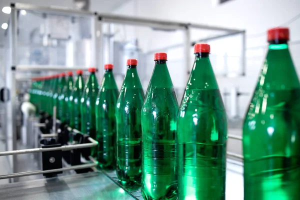 Bottled drinking water being transported on conveyor belt automated machine in beverage factory.