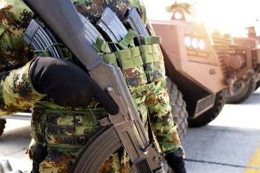 Kamuflaj üniformalı, tüfekli ve nakil aracının yanında duran tanınmamış bir askerin portresi..