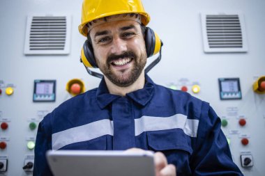 Portrait of smiling industrial electrician engineer standing in power plant.