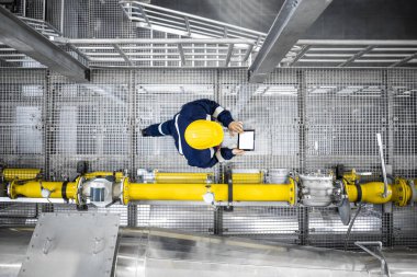 Top view of refinery worker walking by gas pipes, checking gasoline supply and installations in production plant.