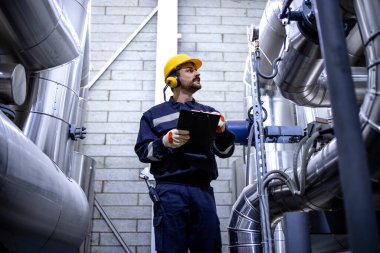 Worker checking pipes in city heating plant.