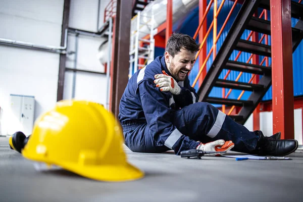 Injury at work. Factory worker fell down and injured shoulder at work.