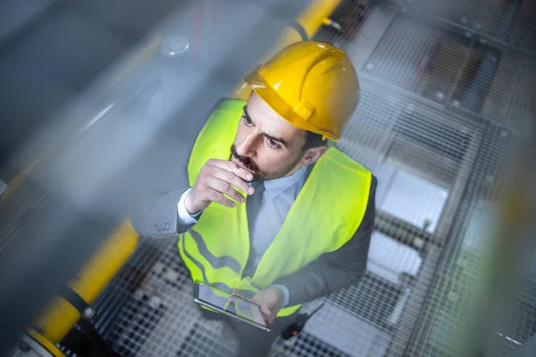 Production manager in suit and hardhat inspecting manufacturing in factory.